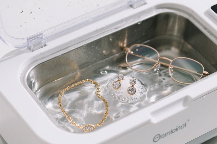Ultrasonic jewelry cleaner bubbling with rings and necklace inside