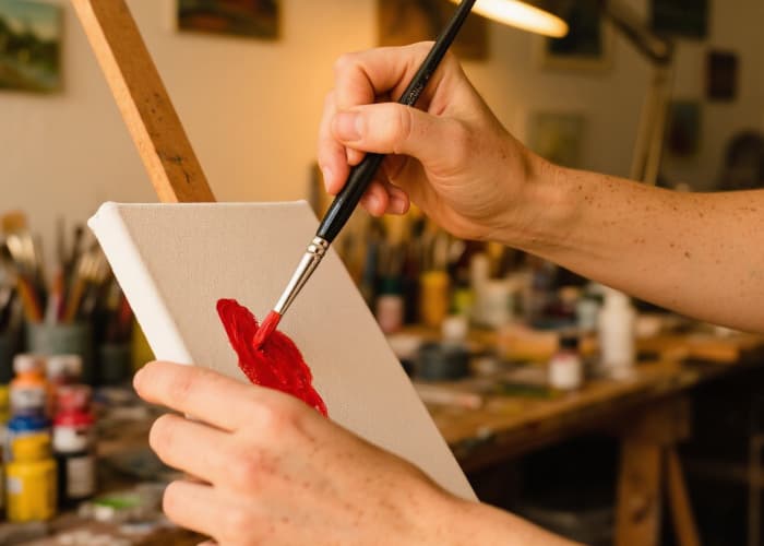 A focused shot of hands working on a craft (clay, paint, wood) in a workshop setting