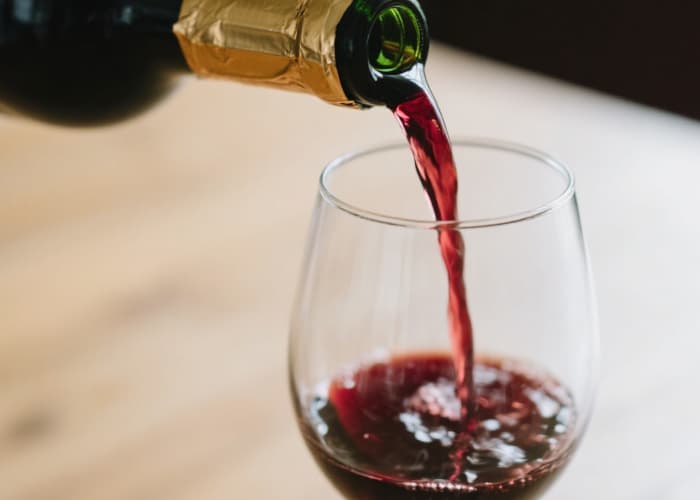 A close-up shot of the pourer spout inserted in a bottle, mid-pour into a glass, showcasing the clean stream